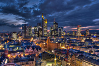 Illuminated cityscape against cloudy sky