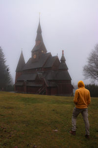 Rear view of man outside temple on field against sky