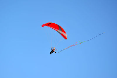 Low angle view of person paragliding against clear blue sky