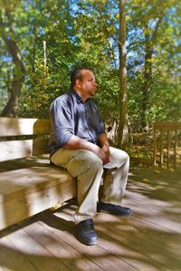 Full length of tensed man sitting on bench at park