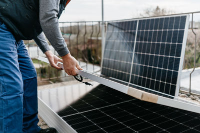 Midsection of man stacking solar panel on roof