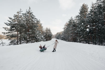 Mother sleds her daughter in a snowy forest