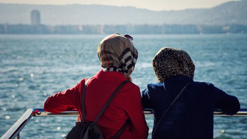 Rear view of women wearing headscarf looking at sea