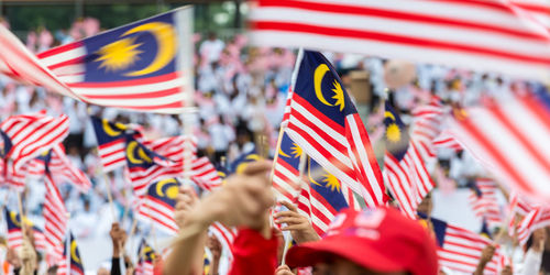 Cropped hands holding american flags on street