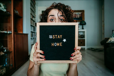 Portrait of woman holding slate with stay home text