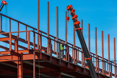 Builders fix iron beams with a crane. frame construction