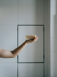 Cropped hand of woman using mobile phone in bathroom