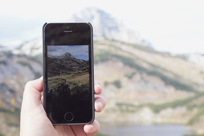 Cropped image of man photographing through smart phone