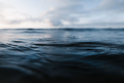 Powerful foamy sea waves rolling and splashing over water surface against cloudy blue sky