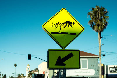 Low angle view of road sign against clear blue sky