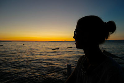 Smiling woman by sea against sky during sunset