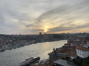 High angle view of buildings by river against sky during sunset