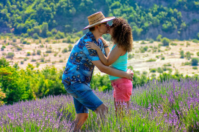 Side view of woman with purple flowers on field