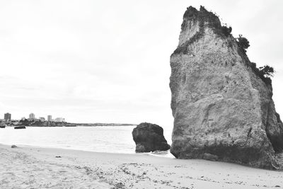 Rock formation on beach against sky