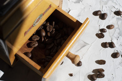 Whole roasted coffee beans in the drawer of a vintage wooden coffee grinder
