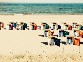 Hooded chairs on beach against sky