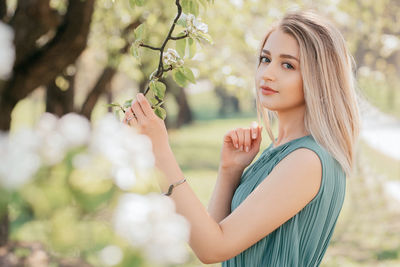 Beautiful young woman holding a apple flowers branch