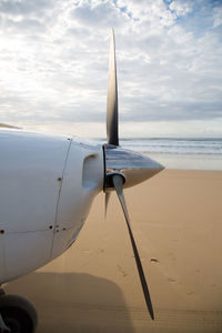 Close-up of airplane on beach against sky