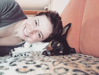 Portrait of smiling woman with dog on bed at home