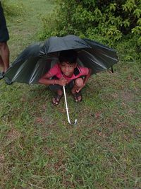 Portrait of boy holding umbrella sitting outdoors