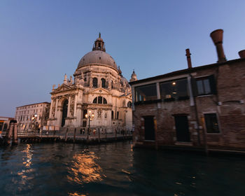 Canal amidst buildings against sky in city