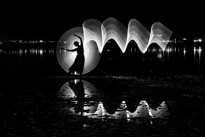 Man standing by lake against sky at night