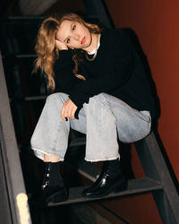 Portrait of young woman sitting on ladder