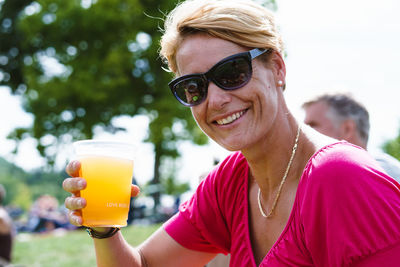 Close-up portrait of mature woman having drink while sitting at park