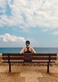 Full length of man sitting on shore against sky