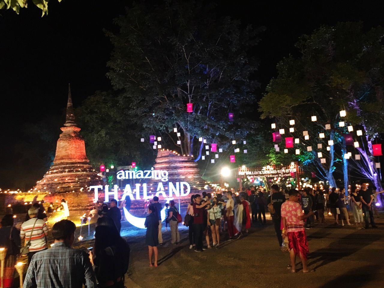 PEOPLE AT ILLUMINATED CITY AGAINST SKY