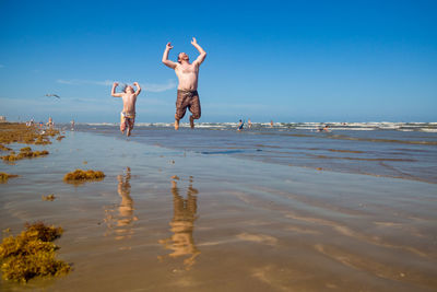 Full length of people on beach against sky