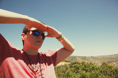 Woman shielding eyes against clear sky on sunny day