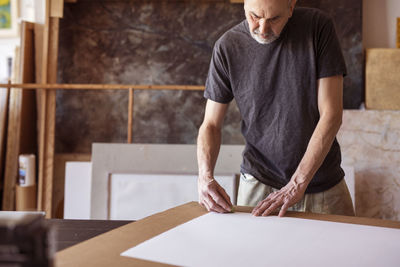 Male artist rubbing on paper in workshop