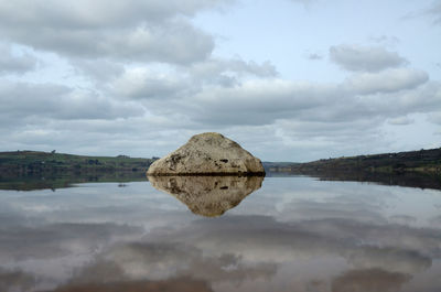 Reflection of rocks in lake against sky