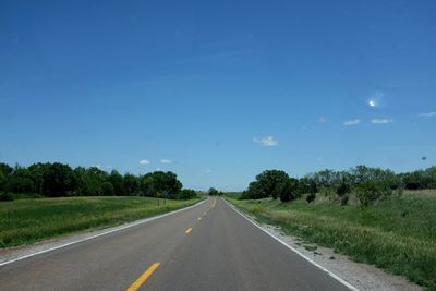 Road passing through landscape against blue sky