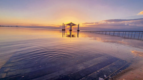 Pier on sea against sky during sunset