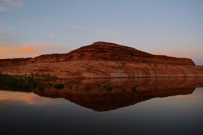 Scenic view of mountain by lake against sky during sunset