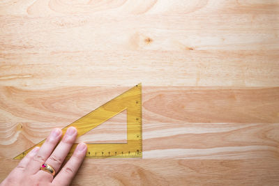 High angle view of person hand holding set square on table