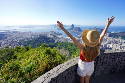 Tourist woman with raising arms on belvedere terrace with guanabara bay in rio de janeiro, brazil