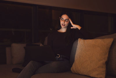 Portrait of young woman sitting on sofa at home