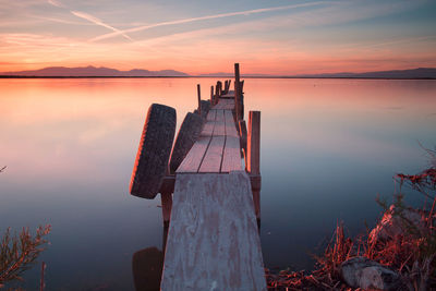 Tires hanging on old wooden jetty over salton sea lake against sky