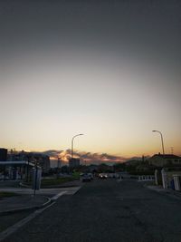 Road by city against sky during sunset