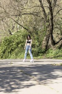 Brunette woman in a sports bra, jeans and pink roller skates in a park