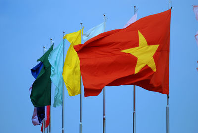 Low angle view of flags against blue sky