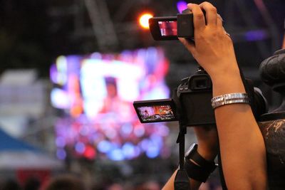 Midsection of woman photographing illuminated smart phone at night