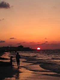 Silhouette man standing on beach against sky during sunset