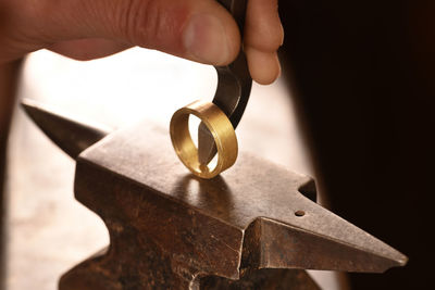 Cropped hand of manual worker hitting metallic ring in factory