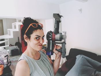 Portrait of young woman photographing at home