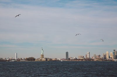 Statue of liberty and city by upper bay against sky