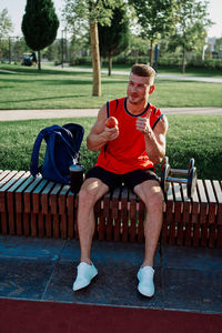 Portrait of smiling friends sitting on bench at park